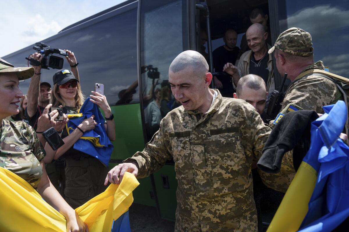 Ukrainian POWs are greeted as they step off a bus. 