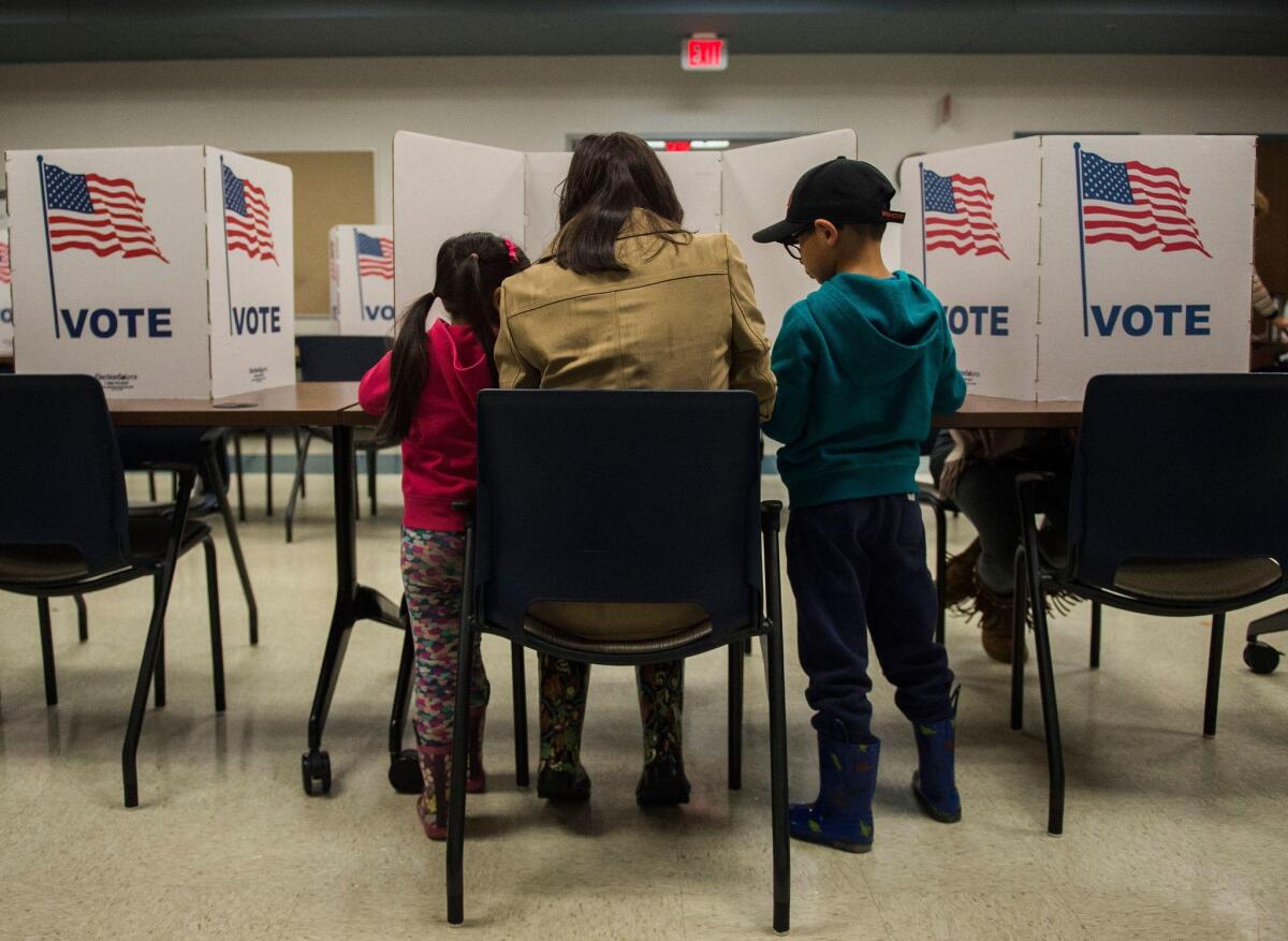 With her children as observers, a woman votes during the midterm elections at the Fairfax County bus garage in Lorton, Va.