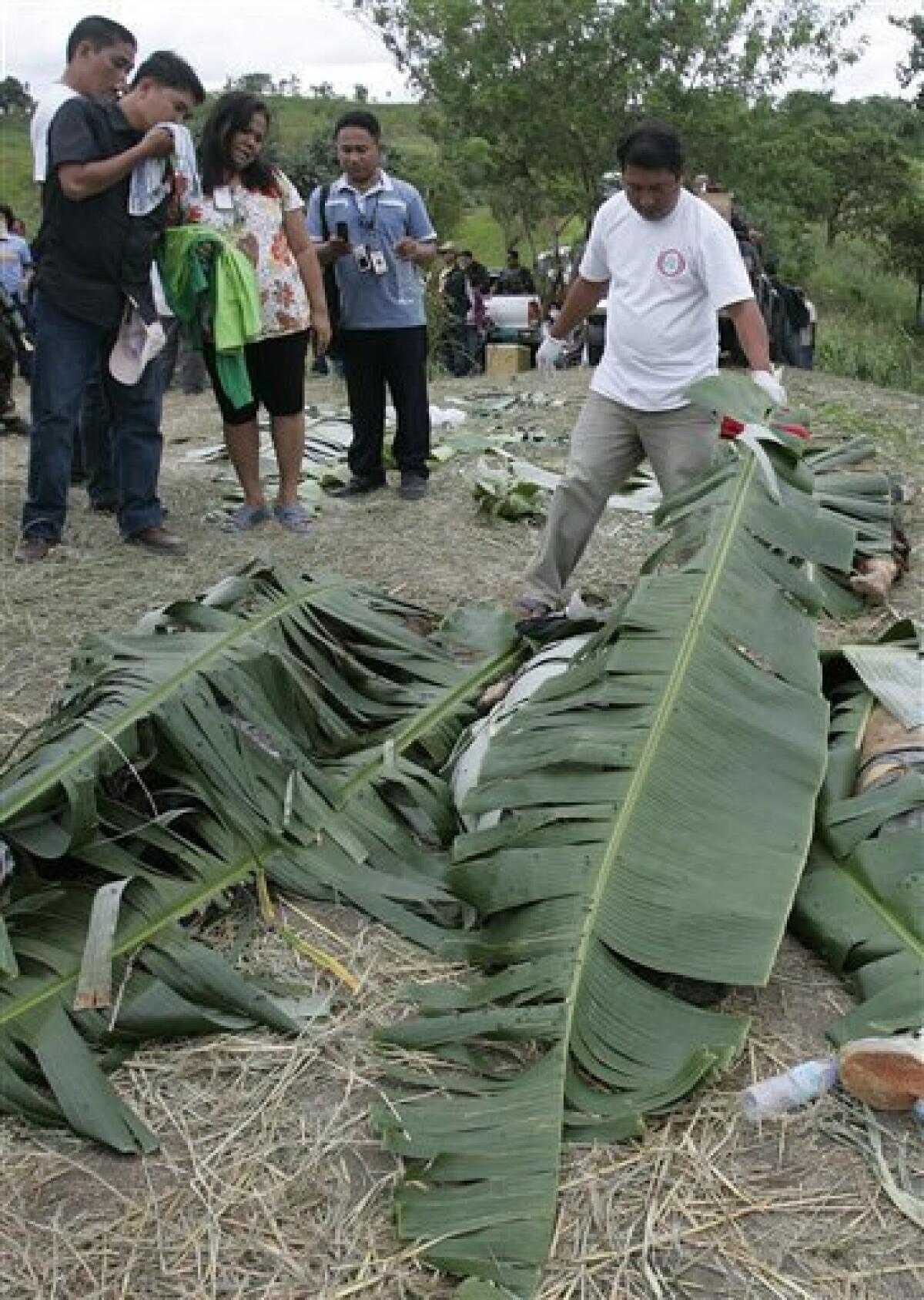 Members of the media try to identify their colleagues who were dumped together with three vehicles along a hillside grave in Ampatuan, Maguindanao province, southern Philippines on Wednesday Nov. 25, 2009. Philippine authorities, under intense public pressure to make arrests in the country's worst election massacre, said Wednesday they are investigating a member of a powerful clan allied with the government along with four police commanders. (AP Photo/Aaron Favila)