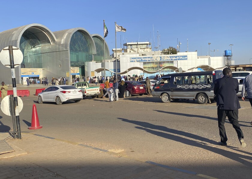 People wait outside Khartoum International Airport, in Khartoum, Sudan, Tuesday, Jan. 14, 2020. A Sudanese official said Tuesday, that security forces have contained an armed protest from within the security apparatus, amid reports of unrest. Earlier Tuesday, workers had told travelers at the airport in Sudan's capital that the facility will be closed temporarily. (AP Photo/Nariman EL-Mofty)