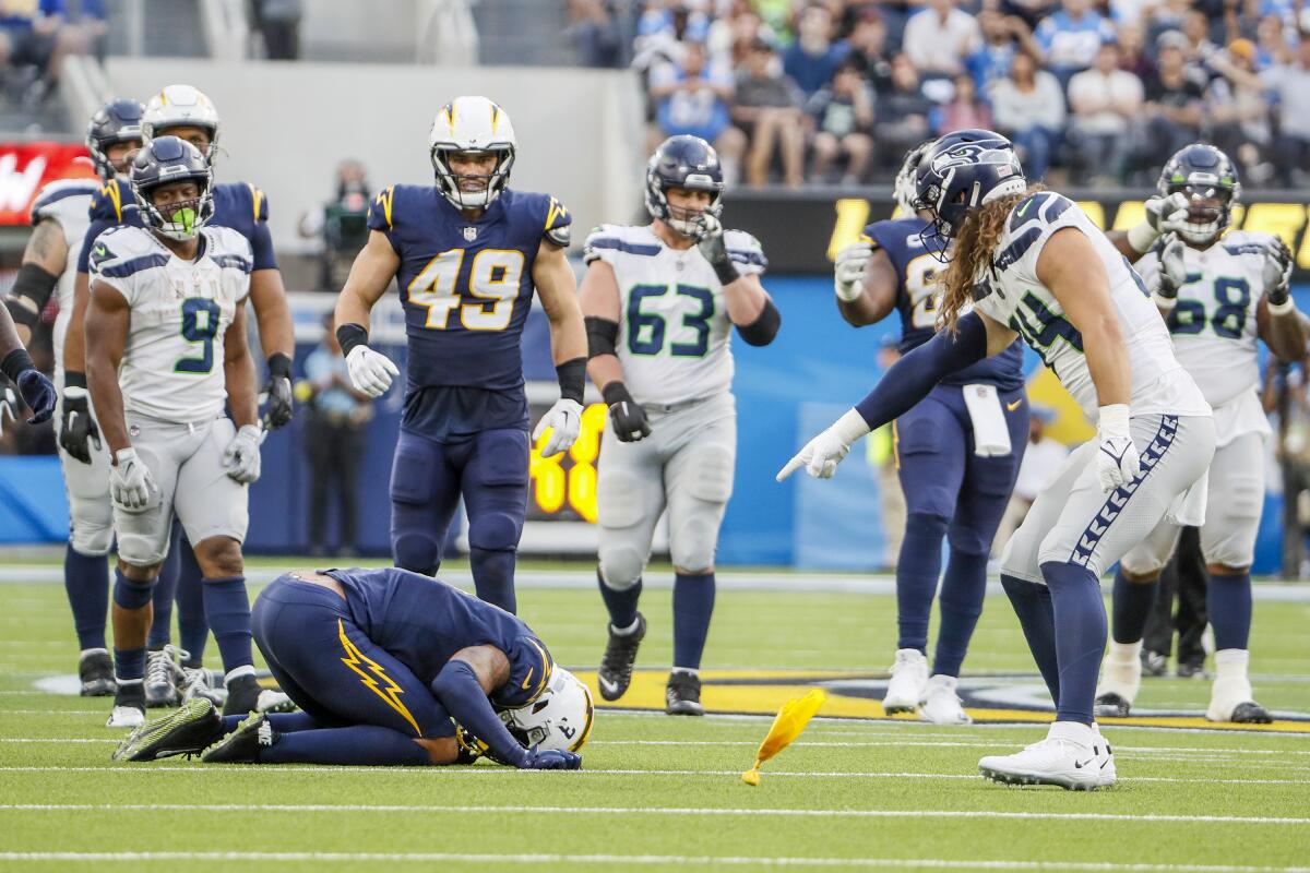 Seattle's Colby Parkinson (84) identifies the penalty culprit, L.A. safety Derwin James Jr., who is flagged for interference