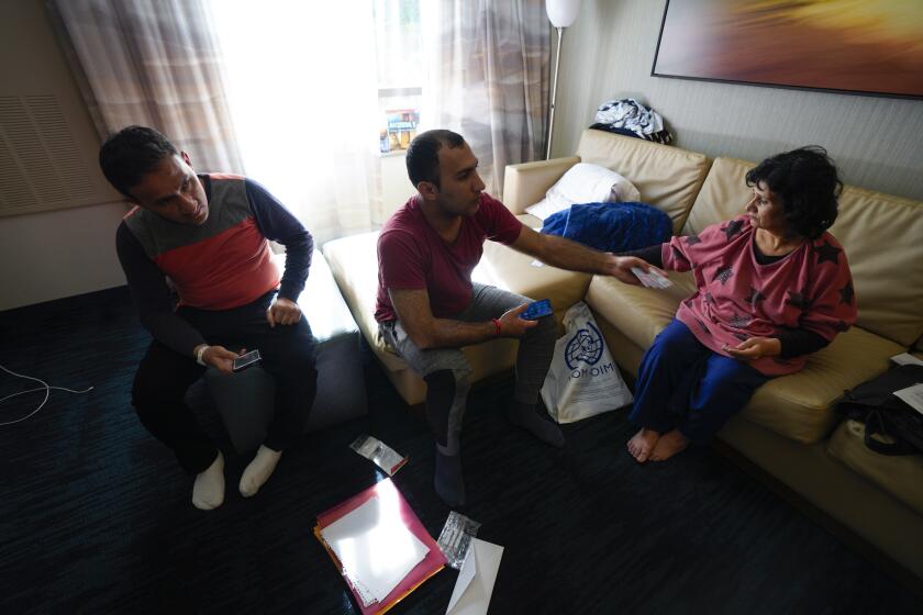 San Diego, CA - February 04: Ahmad Zamir Hussainzada gathers the family’s documents and identification cards for review with Mursel Sabir at their hotel room on Friday, Feb. 4, 2022 in San Diego, CA. (Nelvin C. Cepeda / The San Diego Union-Tribune)