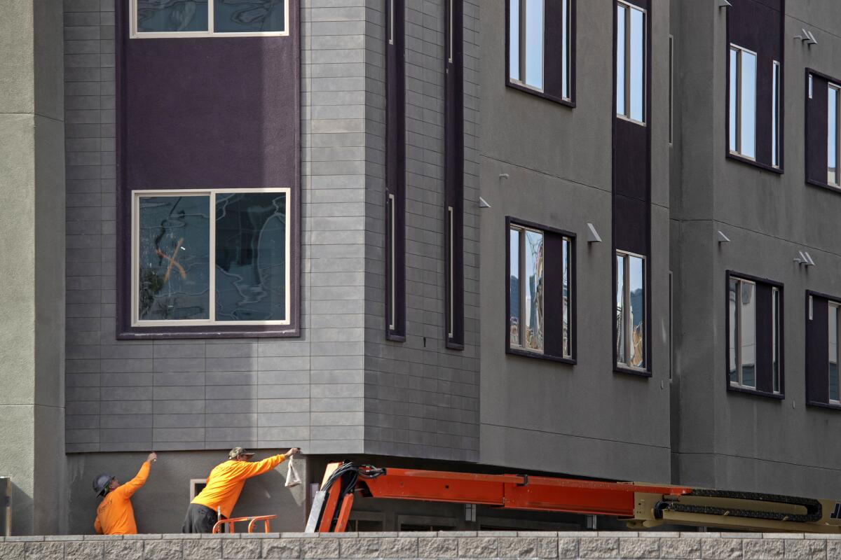 Members of a construction crew work on Central Park West homes and apartments in Irvine.