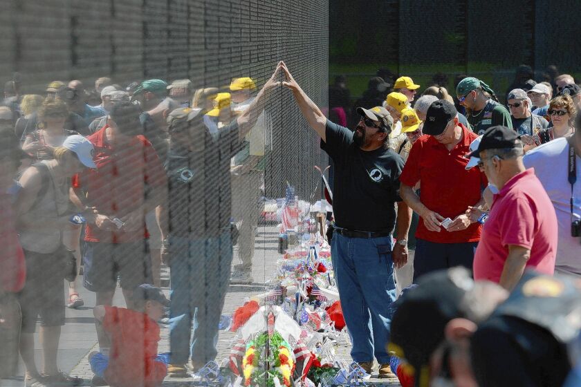 Visitors to the Vietnam Veterans Memorial in Washington. The wall bears the names of 58,300 men and women killed or missing in action.