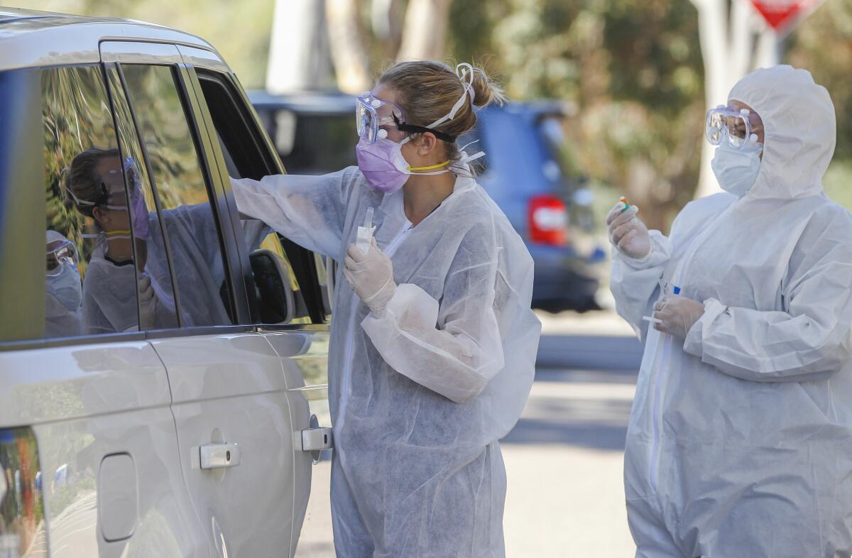 En un lugar de pruebas, los asistentes médicos de la Clínica Covid, Rhiannon Weik (izquierda) y Arely Gutiérrez (derecha) recogen muestras para el examen del Coronavirus COVID-19 en el campus de San Elijo del Colegio Mira Costa, en Cardiff, California.