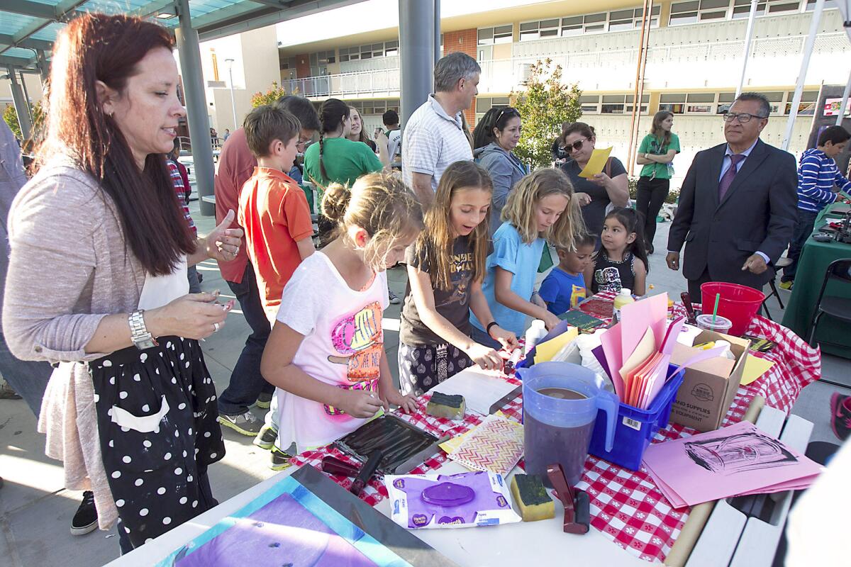 Sonora art teacher Tracy Taber, left, shows kids the craft of print-making during the Newport-Mesa School District's Festival of Learning at Costa Mesa High School on Wednesday.