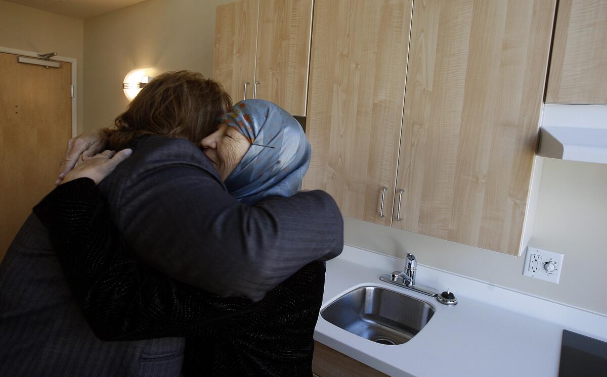 A formerly homeless woman hugs the CEO of the Downtown Women's Center in her new room at their downtown location.