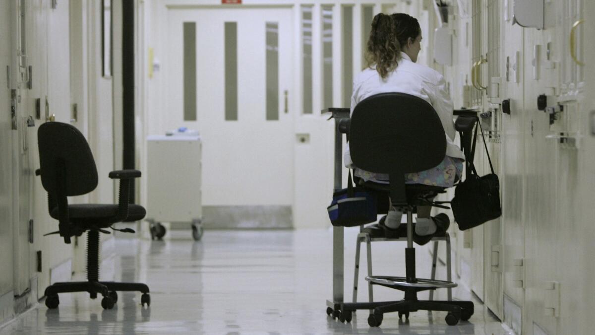 A medical worker sits outside an isolation cell containing an inmate who authorities fear might attempt suicide at California State Prison, Sacramento in Folsom, Calif., on March 30, 2008.
