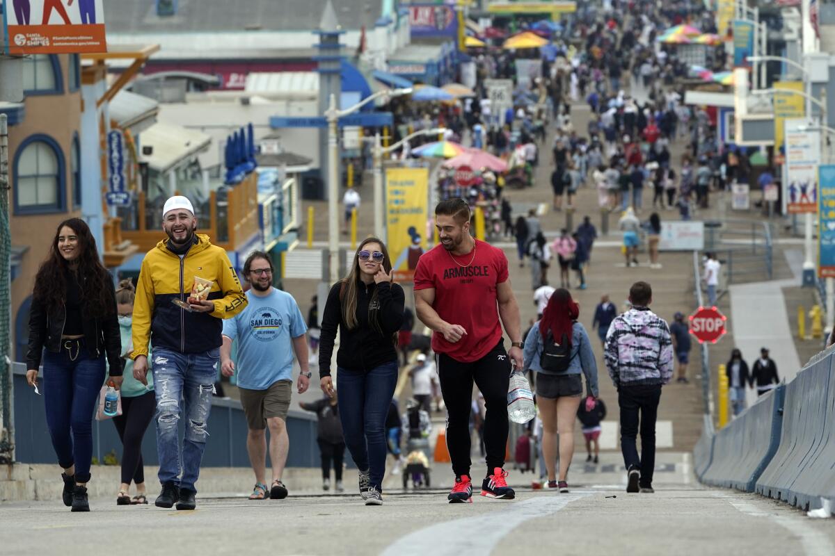 ARCHIVO - En esta foto del 13 de mayo del 2021, visitantes caminan sin mascarillas en el muelle de Santa Monica, California. 