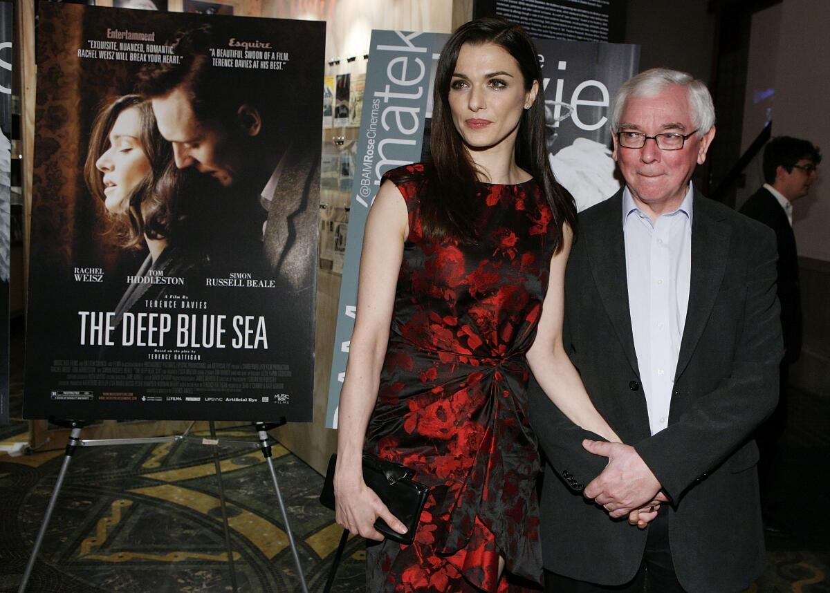 Μια γυναίκα με κόκκινο και μαύρο φόρεμα παρακολουθεί την πρεμιέρα της ταινίας με τον σκηνοθέτη της.