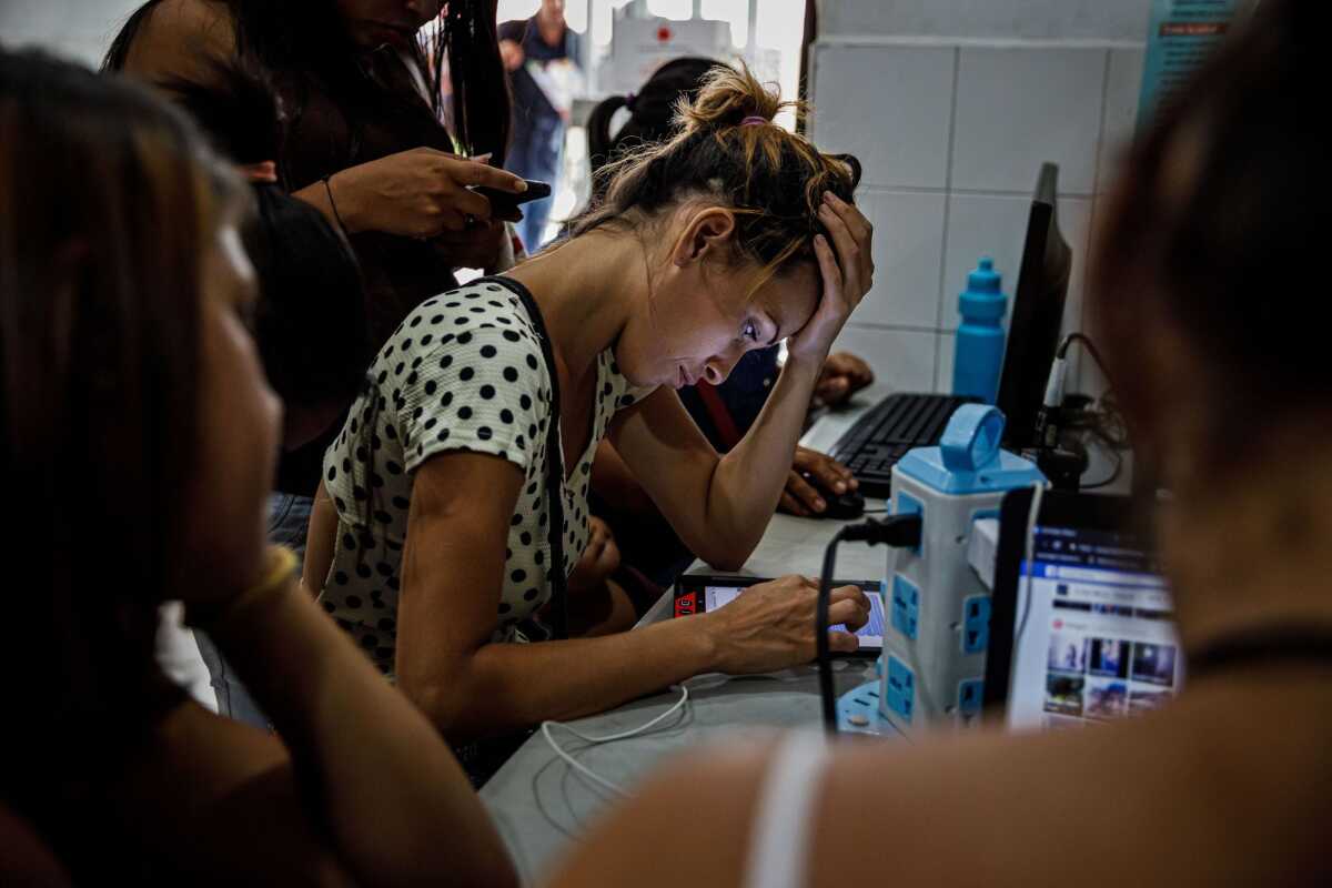 Leidy Paredes envía mensajes a amigos y familiares en Venezuela mientras otros migrantes cargan sus teléfonos en una estación de la Cruz Roja cerca de Cúcuta, Colombia.