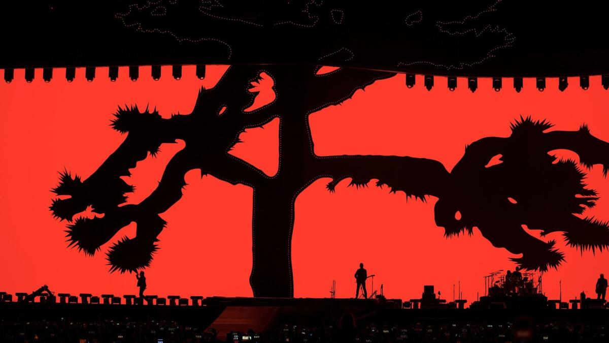 Silhouetted against a red backdrop, U2 performs during the band's 30th-anniversary "Joshua Tree" tour at the Rose Bowl on May 20 in Pasadena. https://lat.ms/2BQGHRm