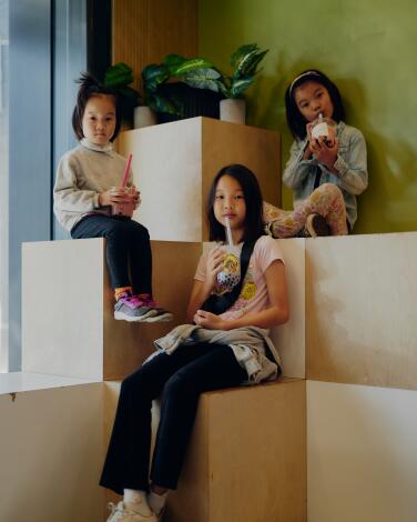 Three young girls sit on stacked-box seating sipping boba tea at Boba the Great.