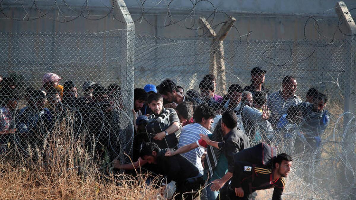 Refugiados sirios irrumpen en Turquía luego de romper una valla en la frontera, el 14 de junio de 2015. En años recientes, Turquía ha construido un muro de concreto en ciertas zonas de la frontera.