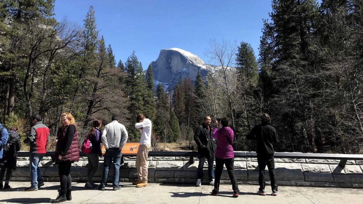 Visitors crowd a bridge to take selfies and photograph the Half Dome in Yosemite National Park in late March.