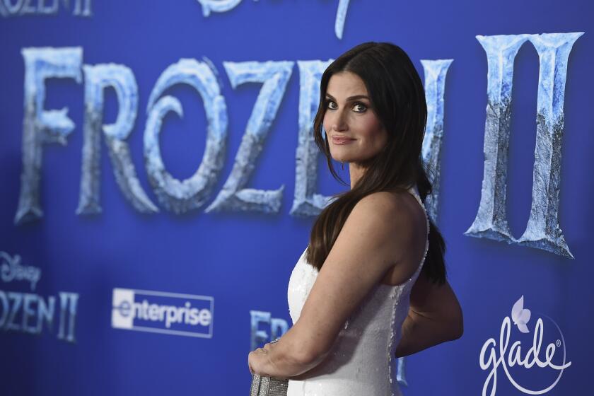 Idina Menzel posing in a white dress against a blue background