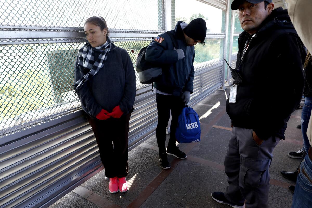 Daimaris Gonzalez, 30, who is pregnant, and Jason, 22, center, both of Cienfuegos, Cuba, at the Gateway International Bridge, as they await being taken into custody by U.S. Customs and Border Protection officers to seek political asylum.
