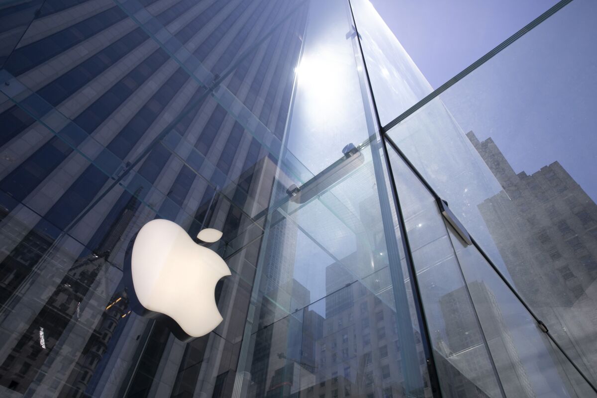 FILE - In this Tuesday, June 16, 2020 file photo, the sun is reflected on Apple's Fifth Avenue store in New York. Apple has managed to shine amid the gloom, putting it on the cusp of becoming the first U.S. company to boast a market value of $2 trillion, just two years after it became the first to reach $1 trillion. With its stock already up 50% this year, the only question among analysts is whether Apple will pass the $2 trillion milestone before the release of its next-generation iPhones in October.(AP Photo/Mark Lennihan, File)