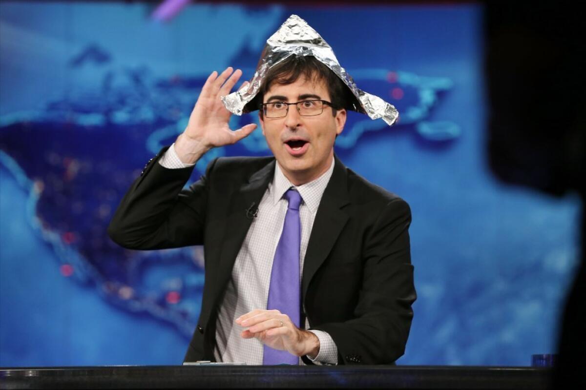 John Oliver puts on a tin foil hat to foil government surveillance on his first night as temporary host of Comedy Central's "The Daily Show."