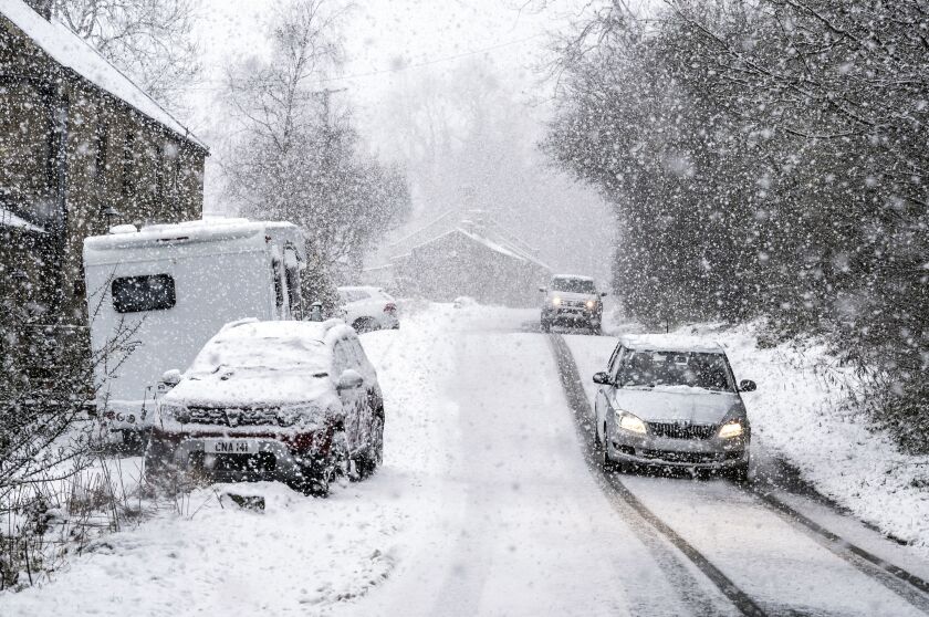 Unos automóviles pasan por una calle nevada en Gunnerside, Inglaterra, el domingo 28 de noviembre de 2021. (Danny Lawson/PA vía AP)