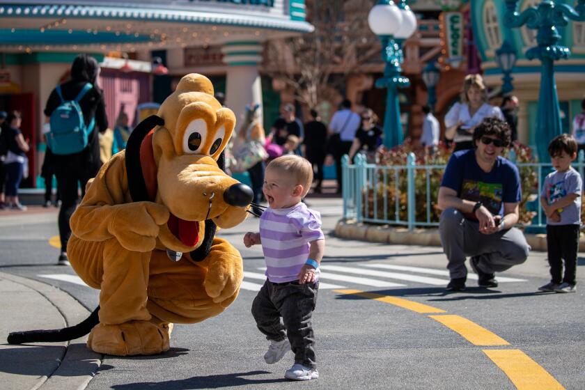 ANAHEIM, CA - MARCH 18: Disney character Pluto entertains a little visitor at Toontown that reopened with a new look in Disneyland on Saturday, March 18, 2023 in Anaheim, CA. (Irfan Khan / Los Angeles Times)