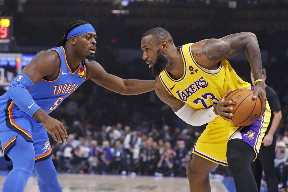 Lakers star LeBron James, right, controls the ball against Oklahoma City guard Luguentz Dort