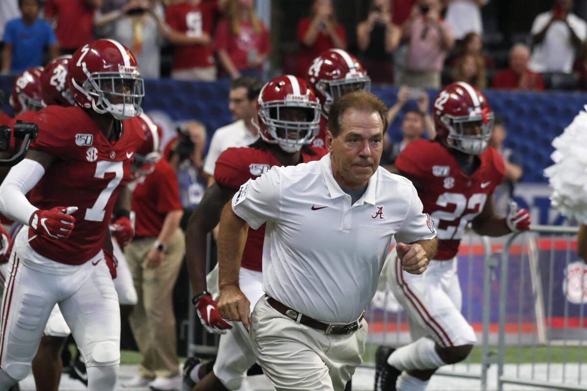 Alabama coach Nick Saban runs onto the field with his players before a game in August 2019.