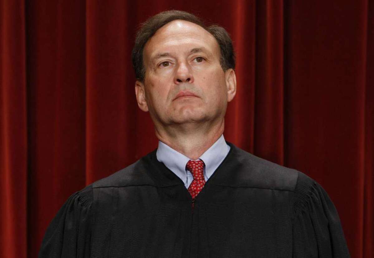 Justice Samuel A. Alito Jr. in black robes in front of a red curtain