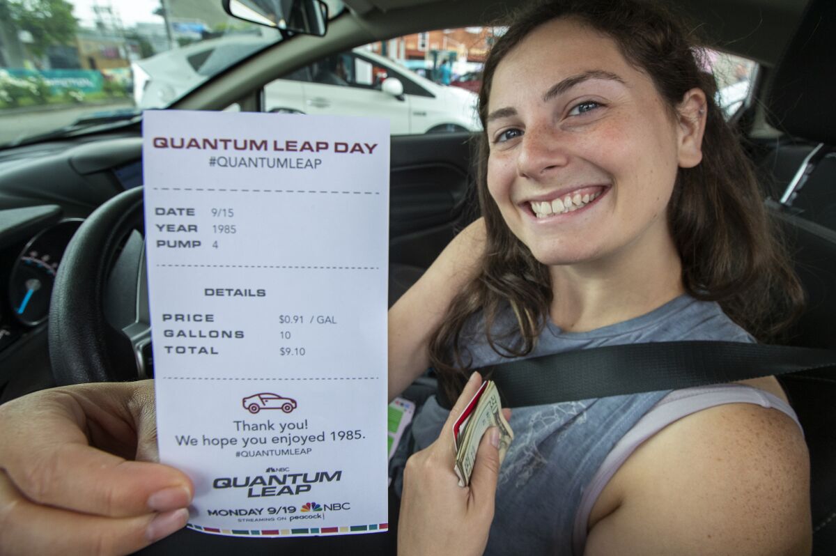 A woman smiles as she shows her receipt for $9.10 after filling up her gas tank.