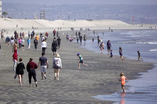 People walk along the beach in Coronado, which is among the few remaining beaches open in San Diego County on March 29, 2020. "We're continuing to monitor the situation," said Mayor Richard Bailey. "The vast majority of the public has been complying with the social-distancing guidelines." To discourage groups of people from congregating at the beach, Coronado has closed nearby public parking lots, removed public bonfire pits, and got rid of volleyball nets and exercise equipment on the beach, Bailey added.