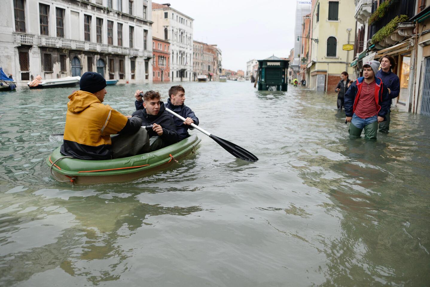 People row a small boat in high water in Venice.