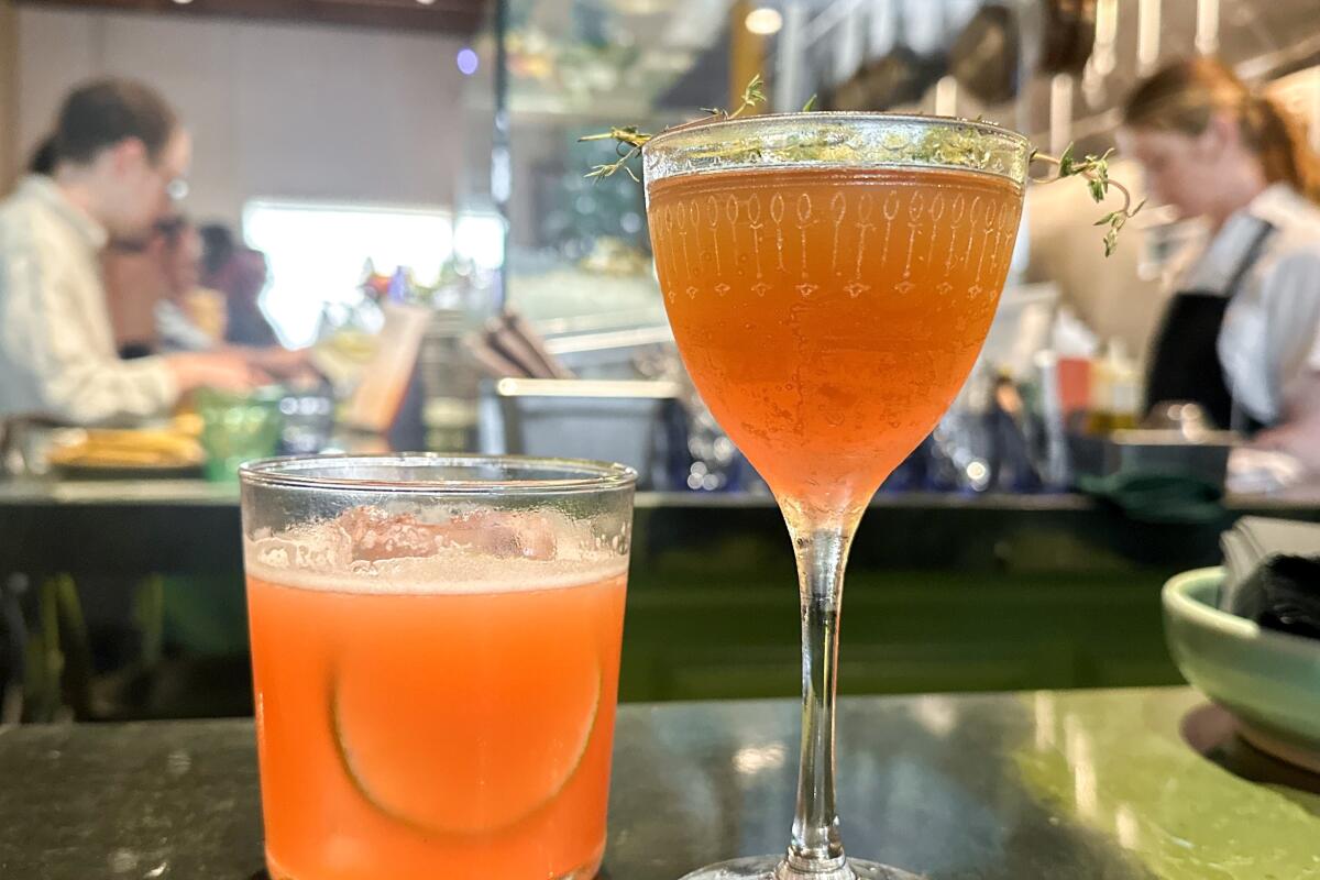 Two orange cocktails in different style glasses on the bar at Mabel's Gone Fishing in San Diego