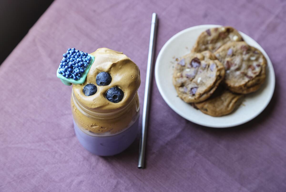 Blueberry Dalgona Coffee, topped with blueberries and adorned with a Mug Buddy Cookie, offers a break from pandemic stress.