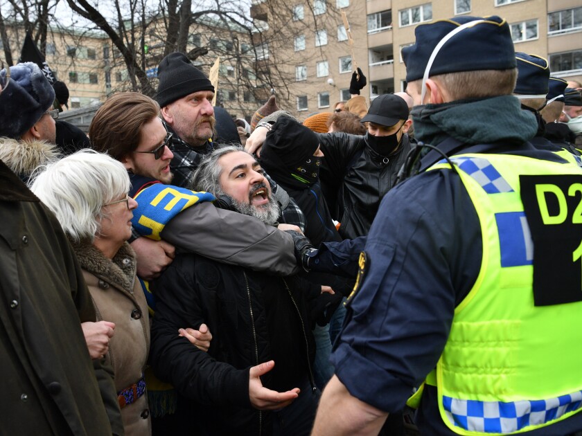 Anti-lockdown protesters face police during a demonstration against the coronavirus restrictions in Stockholm Saturday March 6, 2021. The protest was disbanded by police due to lack of permit for the public gathering. (Henrik Montgomery / TT via AP)