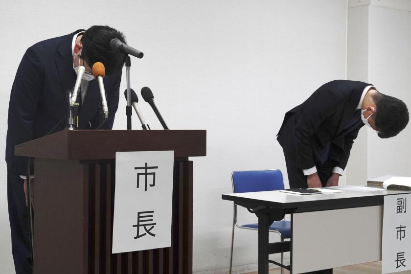 Susono Mayor Harukaze Murata, left, and vice mayor, right, bow during a press conference at the city hall in Susono, Shizuoka Prefecture, central Japan, Monday, Dec. 5, 2022. Japanese police said Monday that they have arrested three teachers at a nursery school in central Japan on suspicion they routinely abused toddlers, such as hitting their heads, holding them upside down and locking them up in a bathroom, a case that triggered outrage across the nation. (Kyodo News via AP)