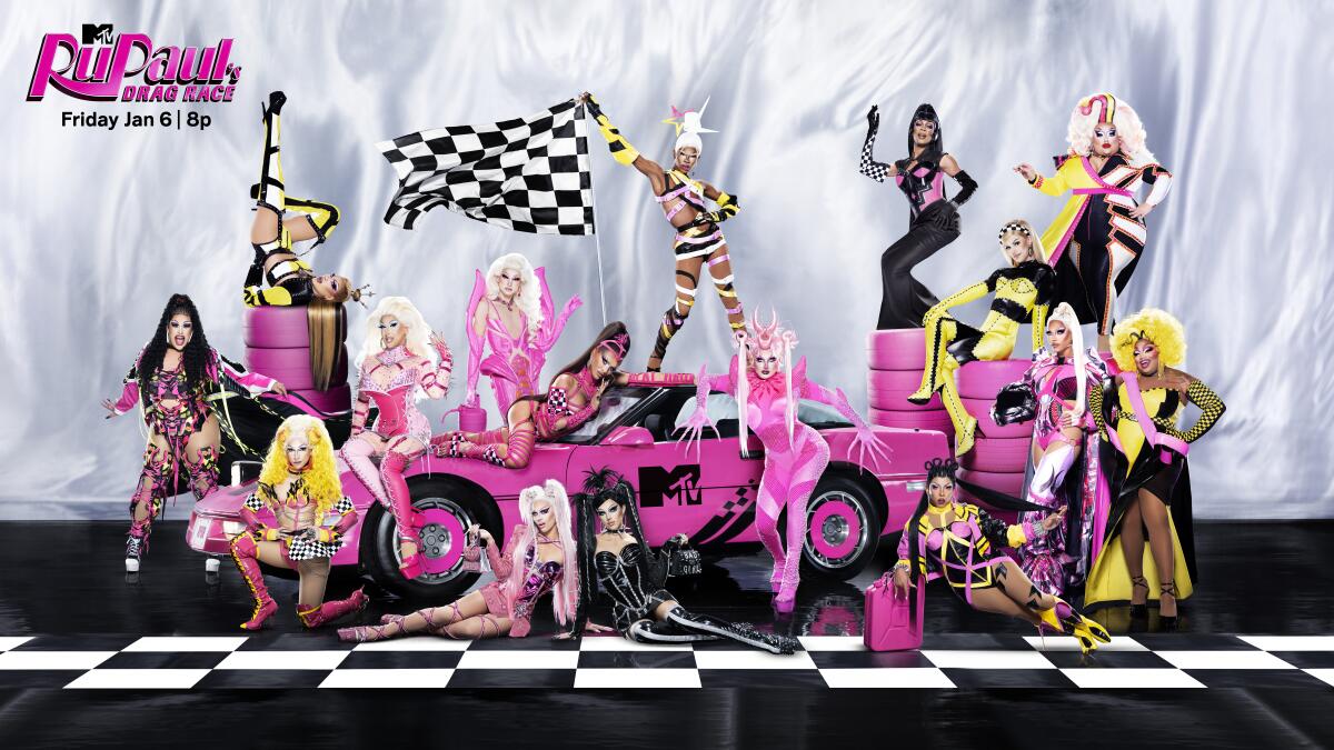 Sixteen drag performers pose around a hot pink car