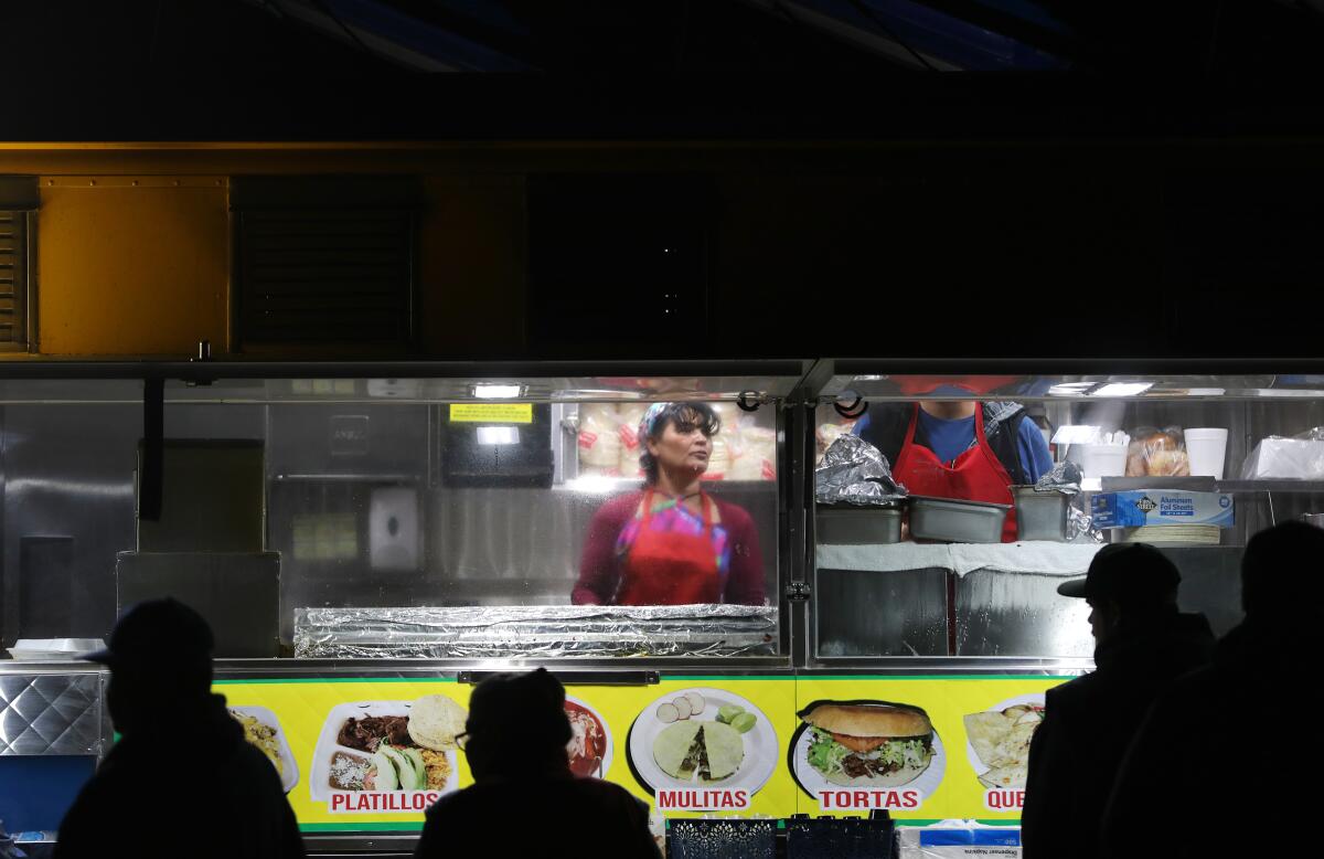 María Cárdenas cocina en el camión de Tacos La Madrina estacionado en Hesperia.