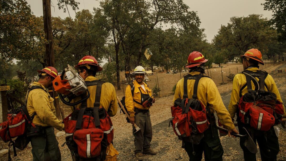 Frederico Rocha Sr., center, leads his firefighters as they mop up hot spots near homes in Redding, Calif., on July 30, 2018.