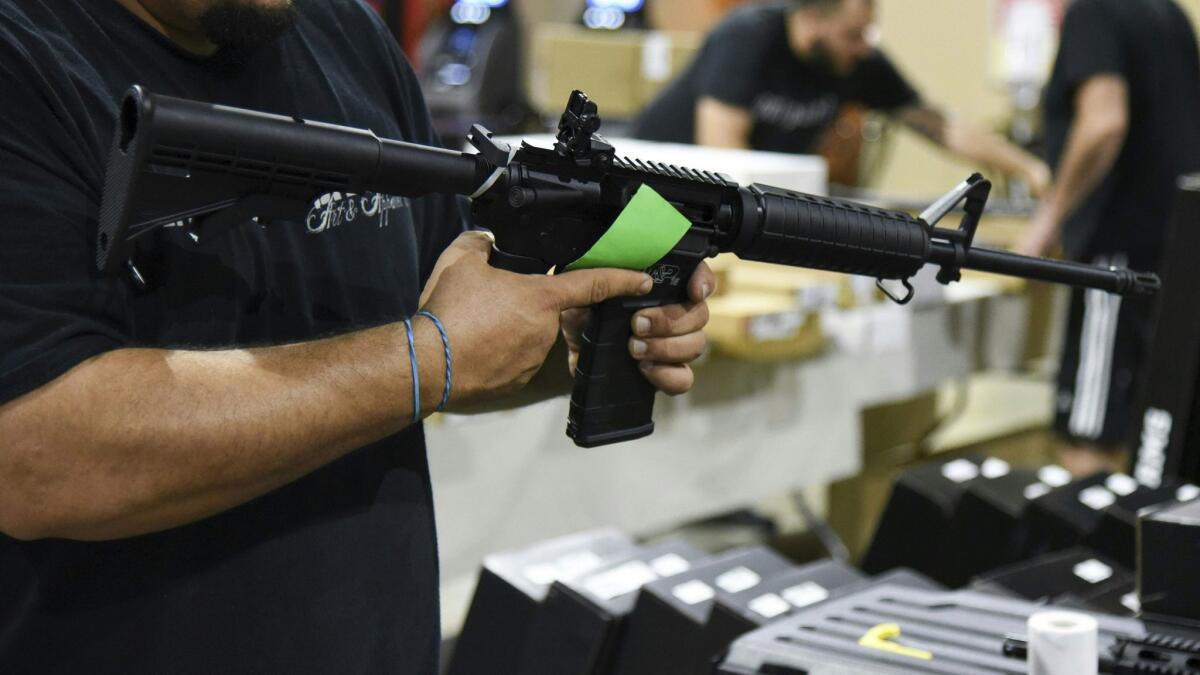 Domingo Martin demonstrates an AR-15 rifle on Feb. 16, 2018, during preparations for the South Florida Gun Show at the South Florida Fairgrounds in Miami.