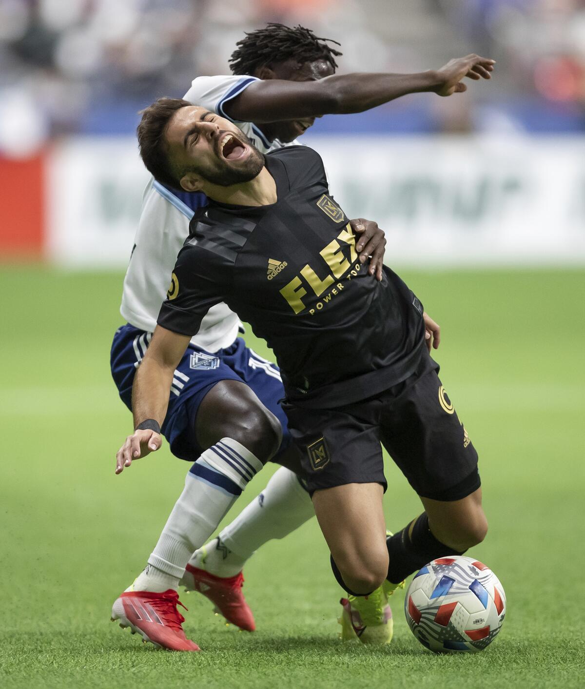 Los Angeles FC's Diego Rossi, front, reacts after being taken off the ball by Vancouver Whitecaps' Janio Bikel during the first half of an MLS soccer match Saturday, Aug. 21, 2021, in Vancouver, British Columbia. (Darryl Dyck/The Canadian Press via AP)