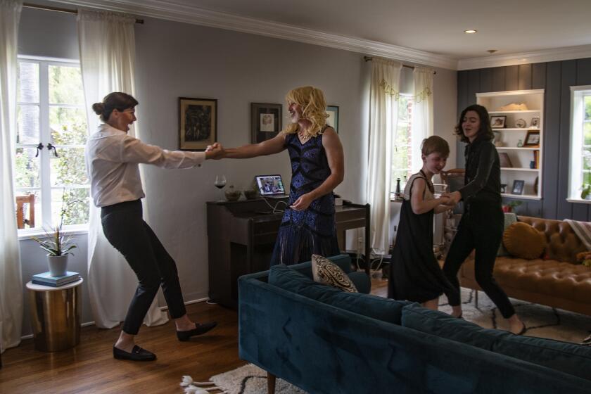 Dancing in their living room, the Stowe family dresses in prom attire with role-reversal to celebrate a nephew's prom that was canceled during the coronavirus pandemic on April 5, 2020 in Riverside, California. The nephew and his family living of Rancho Santa Margarita are connected via a video feed on the laptop in the living room. From the left; Julie Stowe her husband Matt, son Dean,9, and daughter,14. The Stowe family has been dressing in costumes for the past three consecutive Sundays to to keep some fun in their lives, add a distraction and enjoy more family time. "We are trying to find little glimmers," Julie Stowe said. "This whole thing is horrible, but hoping a lot of good will come out of it."