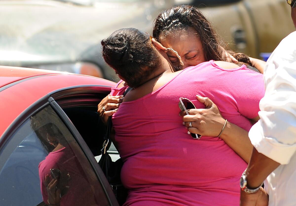 Rodney King's daughters Candice, left, and Lora console each other outside their father's Rialto home after he was found dead in his swimming pool.
