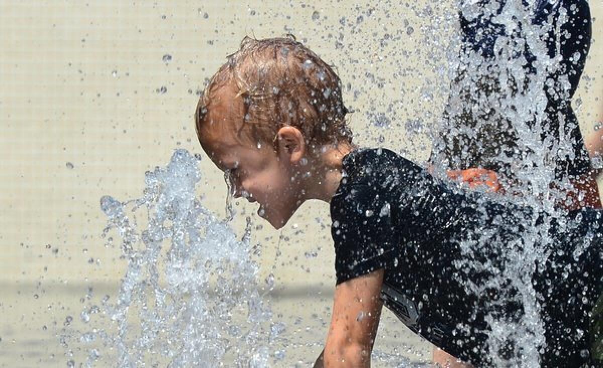 A child cools off Thursday while playing in the fountains at California Plaza in downtown Los Angeles.
