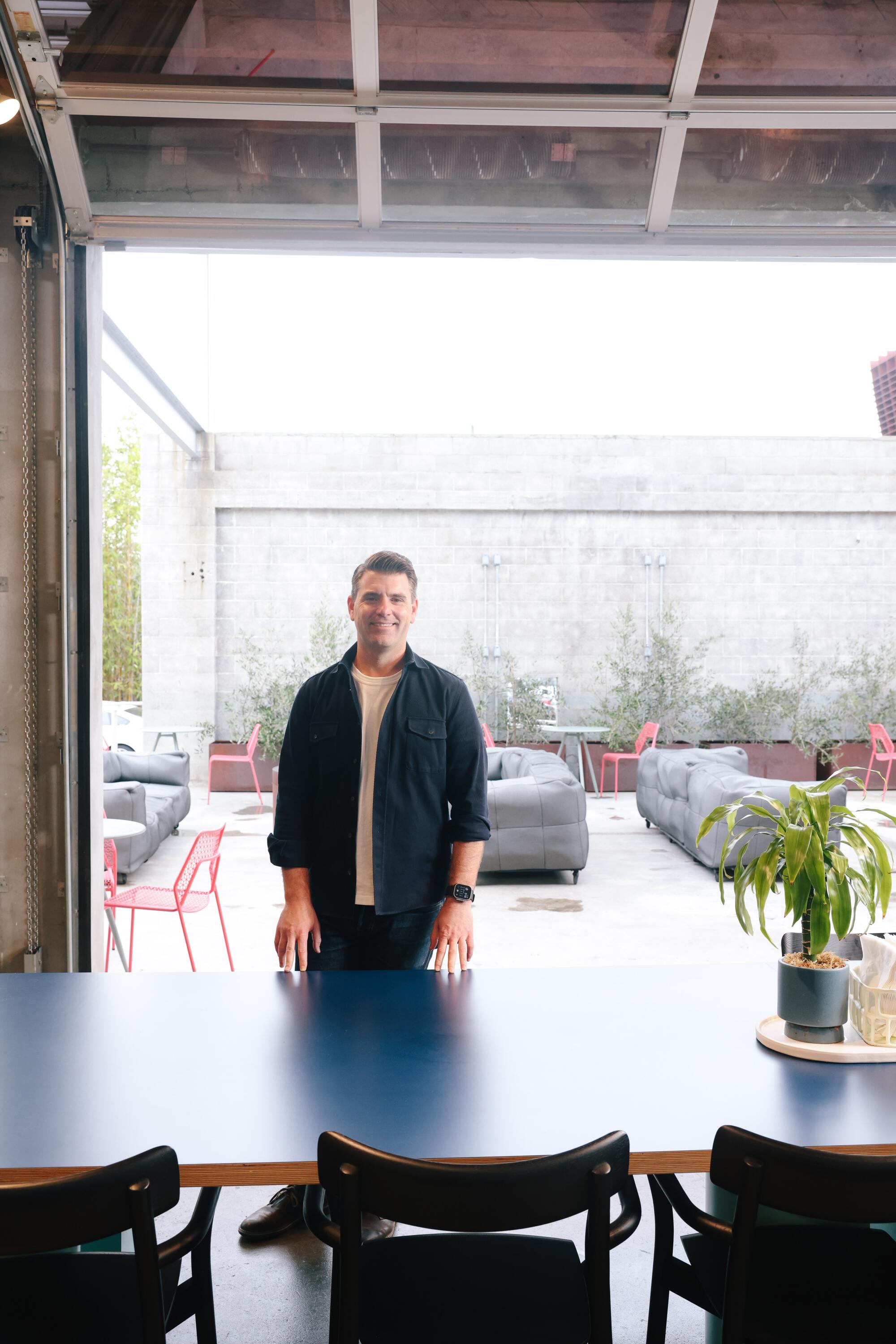 A man stands at a table in an empty dining courtyard.