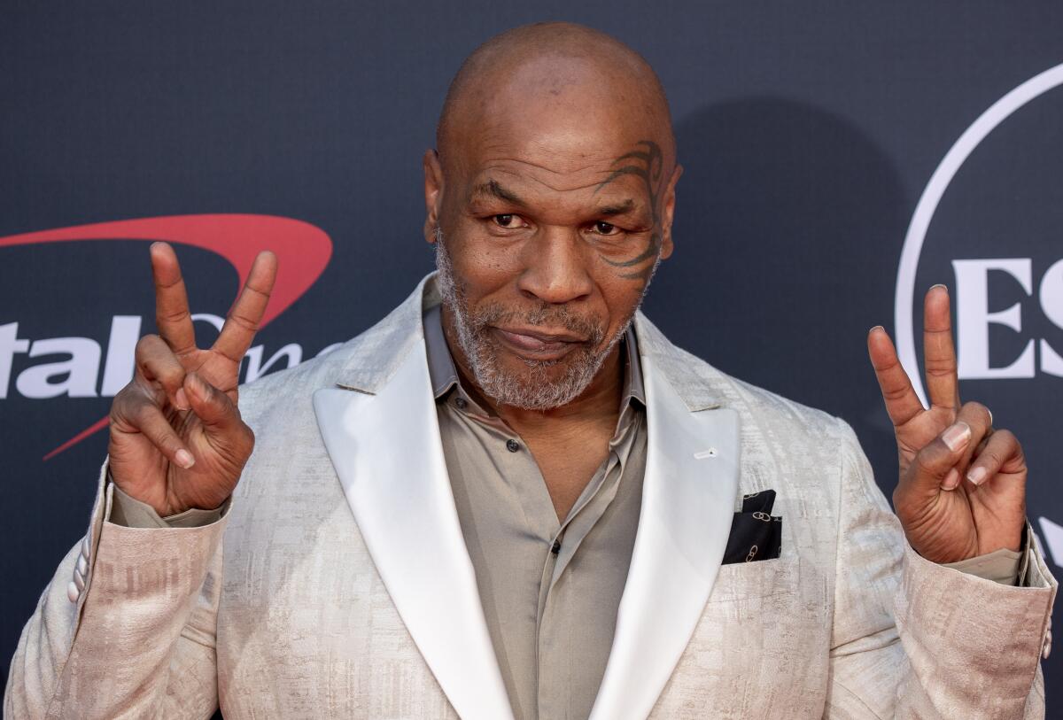 Mike Tyson gives peace signs with both hands as he arrives on the red carpet at the 2023 ESPY Awards.