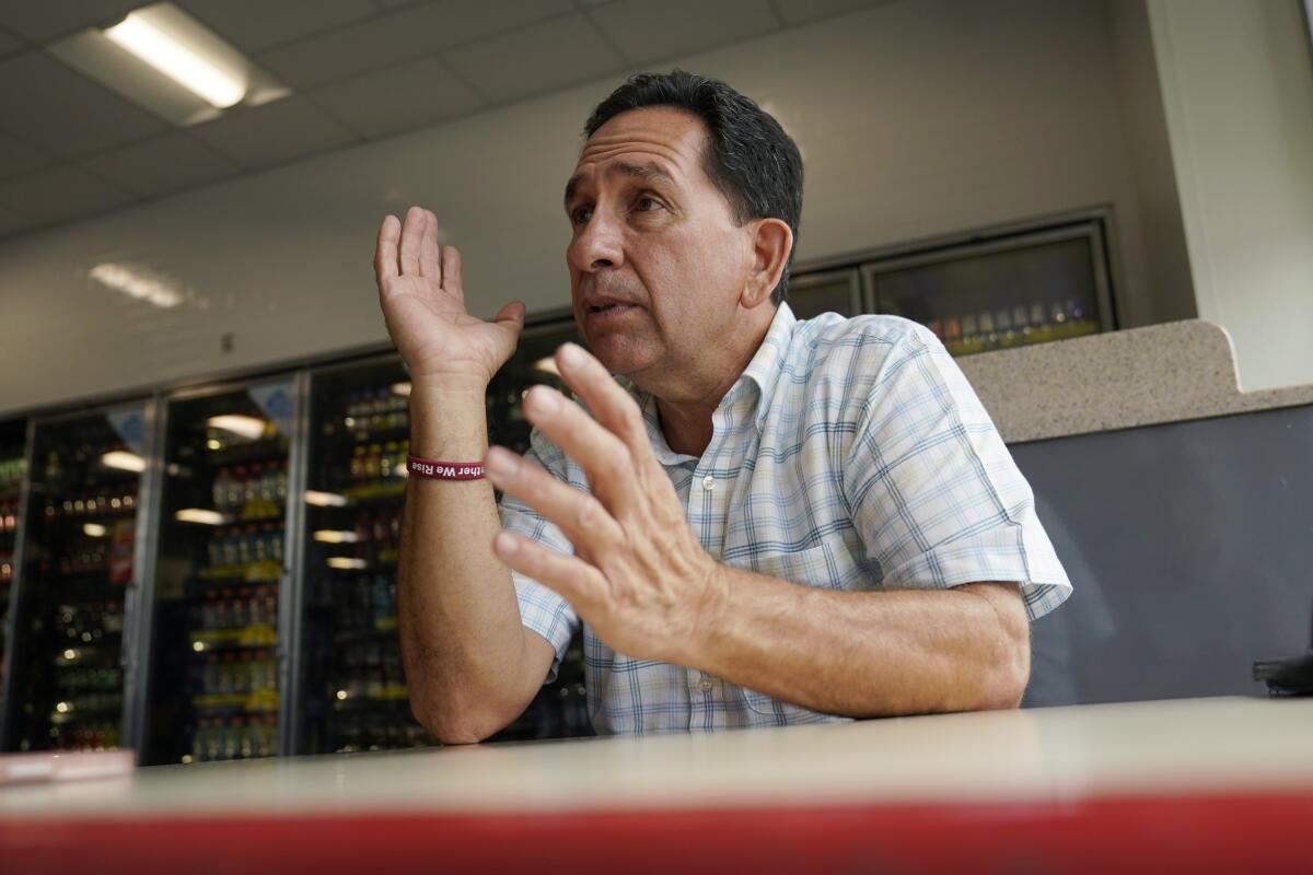 A man gestures while sitting at a table and talking.