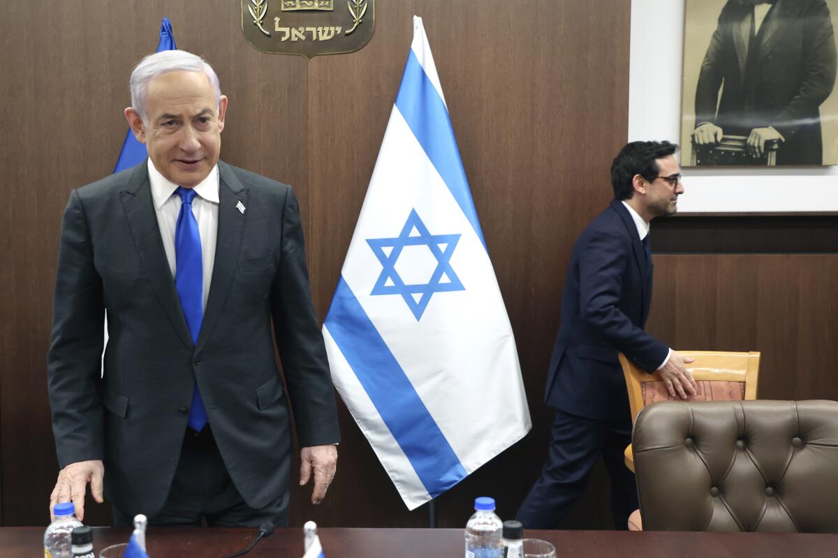El primer ministro israelí Benjamin Netanyahu, izquierda, se acerca a su silla 
