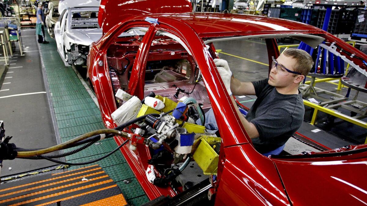 An autoworker installs parts on a Toyota Camry in the trim section at the Toyota factory in Kentucky.
