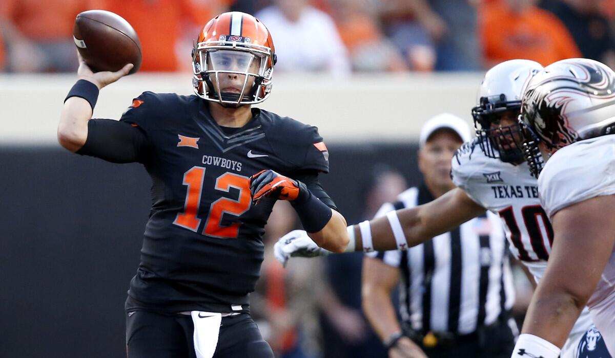 Oklahoma State quarterback Daxx Garman passes under pressure from Texas Tech defenders in the first quarter Thursday night.