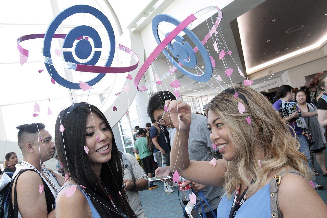 Madelin Cabalu, right, and her sister Melanie Cablu, try to untangle their headdresses that resemble Pokemon Go stops after security guards dispersed them and a large crowd of Pokemon Go players, who gathered on a rumor of being able to capture a rare Pokemon being released from the Pokemon Go pane